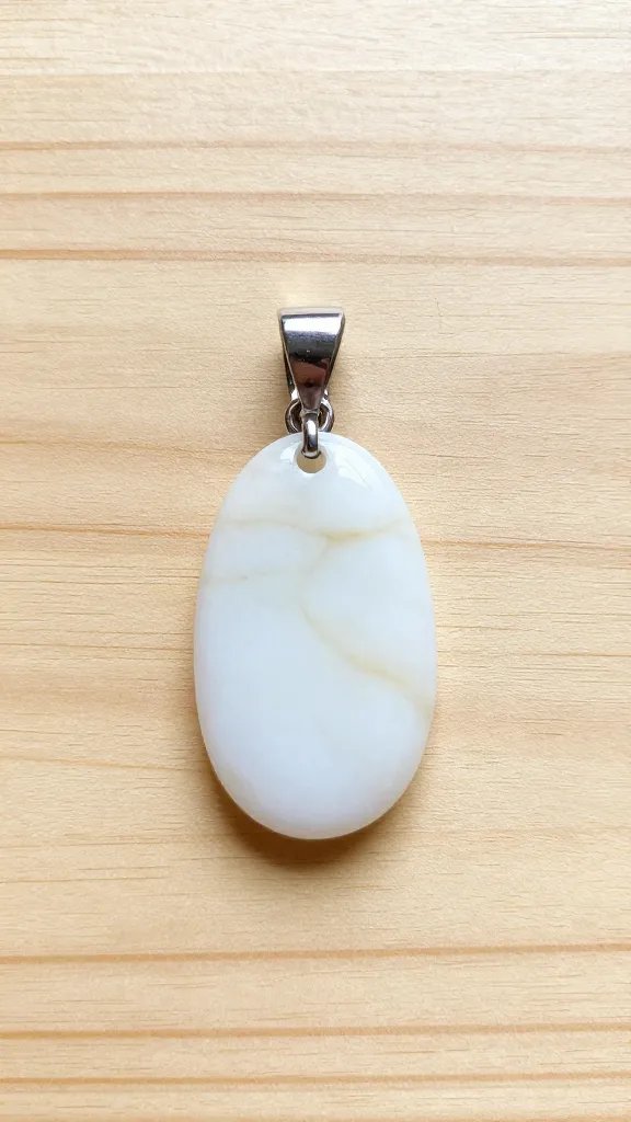 overhead shot of a handmade jewelry pendant on a wooden craft mat